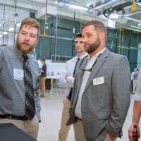 A student explains something on a computer screen to guests at the Engineering Design Project Preview